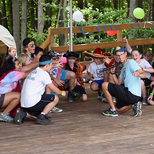 Kids and camp leaders crouching on a deck